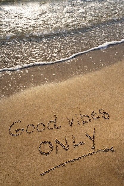 Plage avec message “Good vibes only” écrit dans le sable