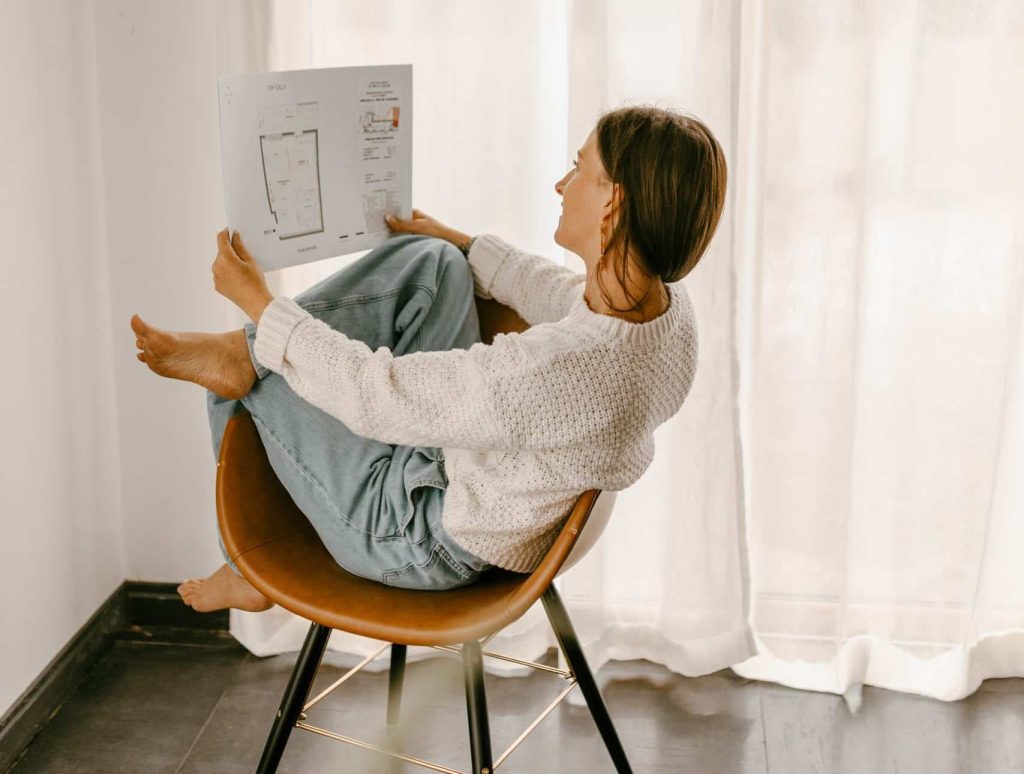 Femme assise sur une chaise consultant un plan d’aménagement