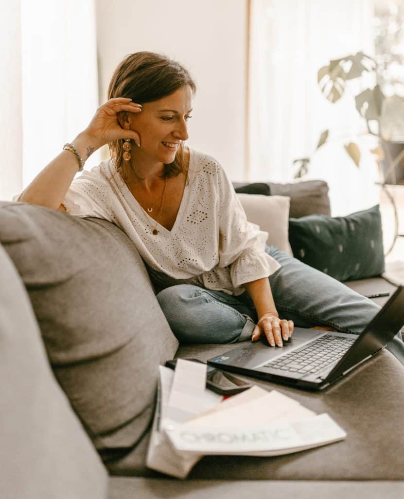 Femme posée sur un canapé consultant son projet de décoration sur son ordinateur