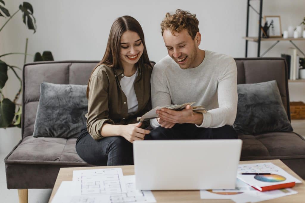 Couple assis sur un canapé qui feuillette leur projet de décoration