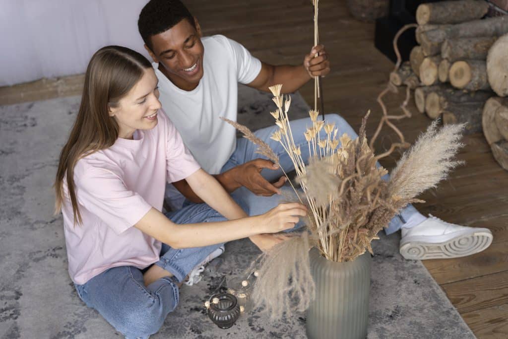 Couple assis par terre installant des plantes dans leur intérieur